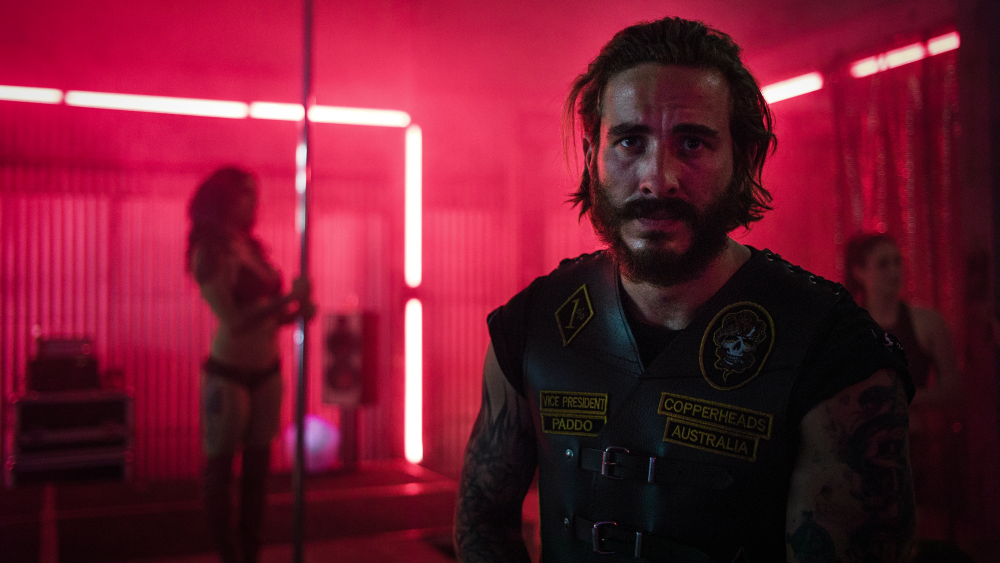 Man in vest with intense look, neon red club background