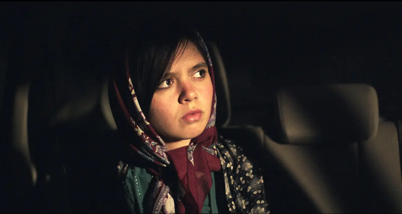 Young girl in hijab looks thoughtful in car at night